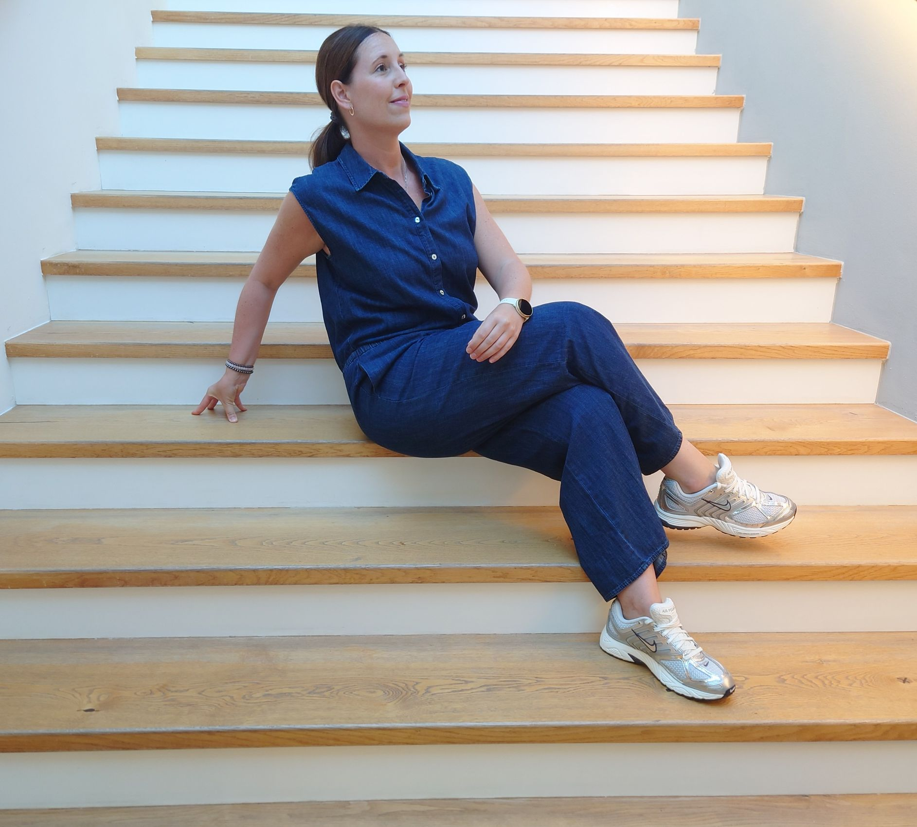 Eine Person dribbelt mit gespreizten Beinen einen Fußball auf einem grünen Feld in der Nähe eines Tores und von Bäumen.