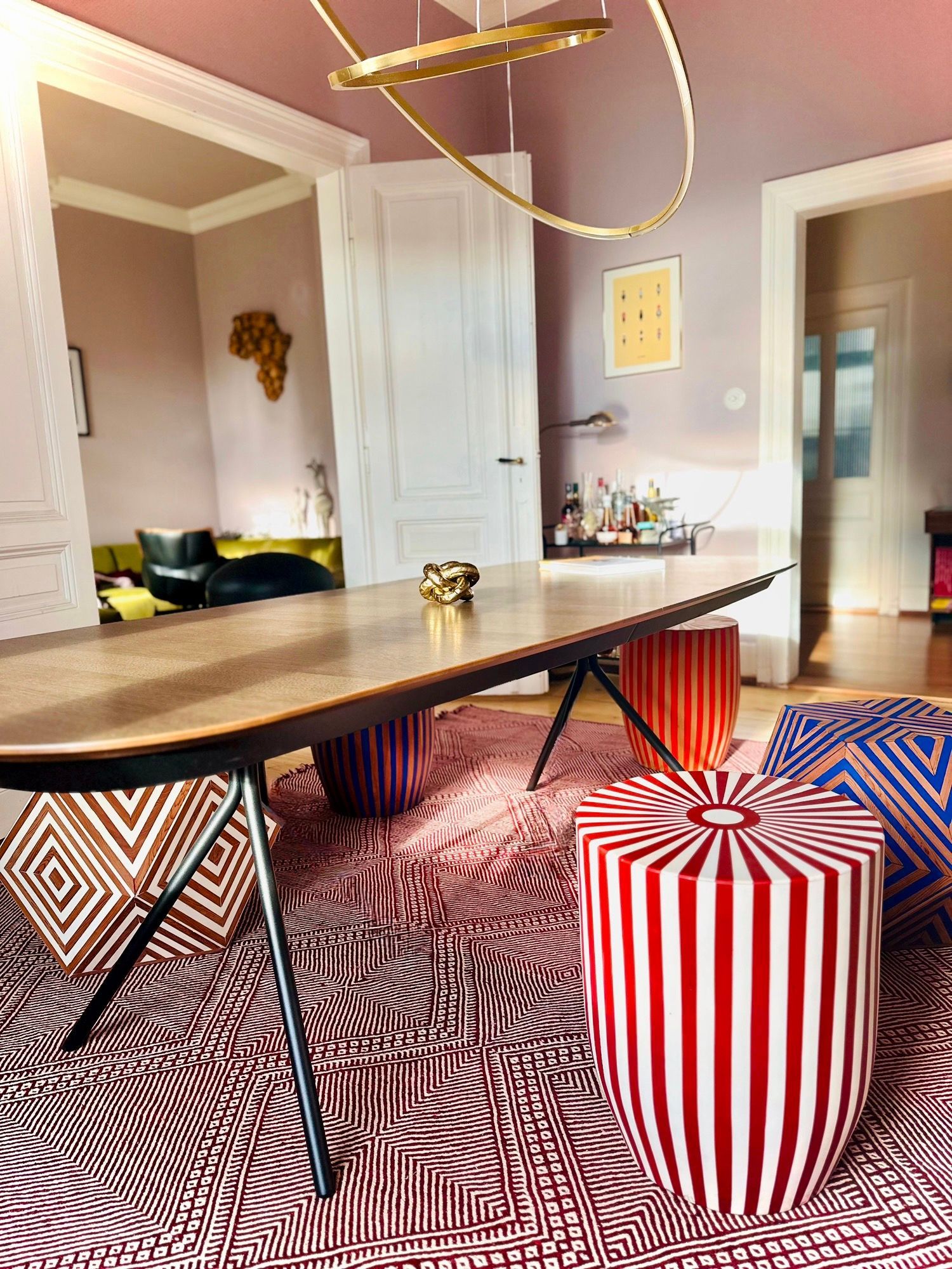 Ein gelb und braun gestreifter Hocker mit zwei Schnapsflaschen darauf.