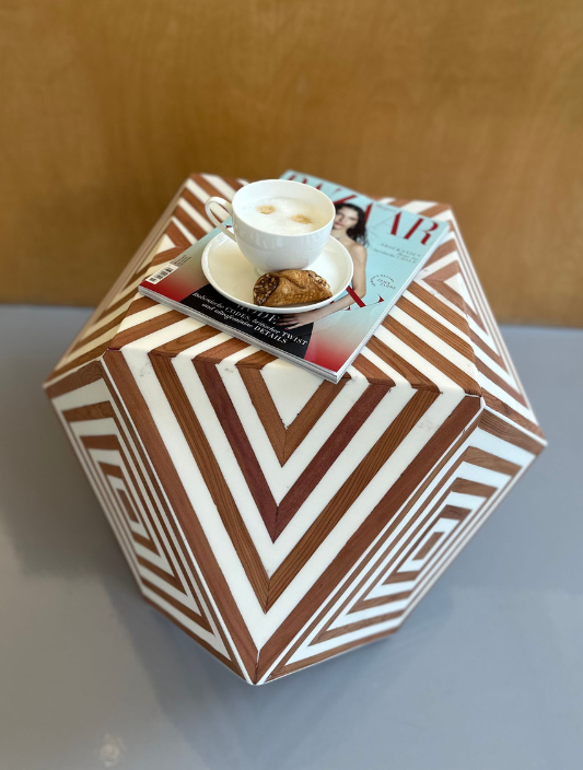 Eine braun-weiß gestreifte Schachtel mit einer Tasse Kaffee und einer Zeitschrift darauf.