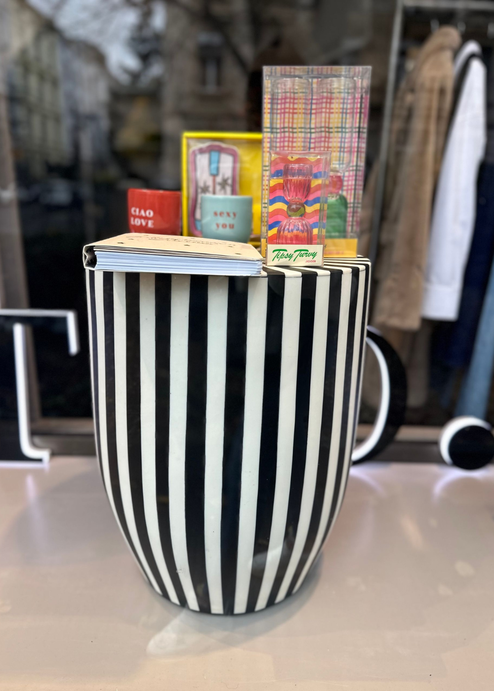 Eine schwarz-weiß gestreifte Tasse gefüllt mit Süßigkeiten und Büchern