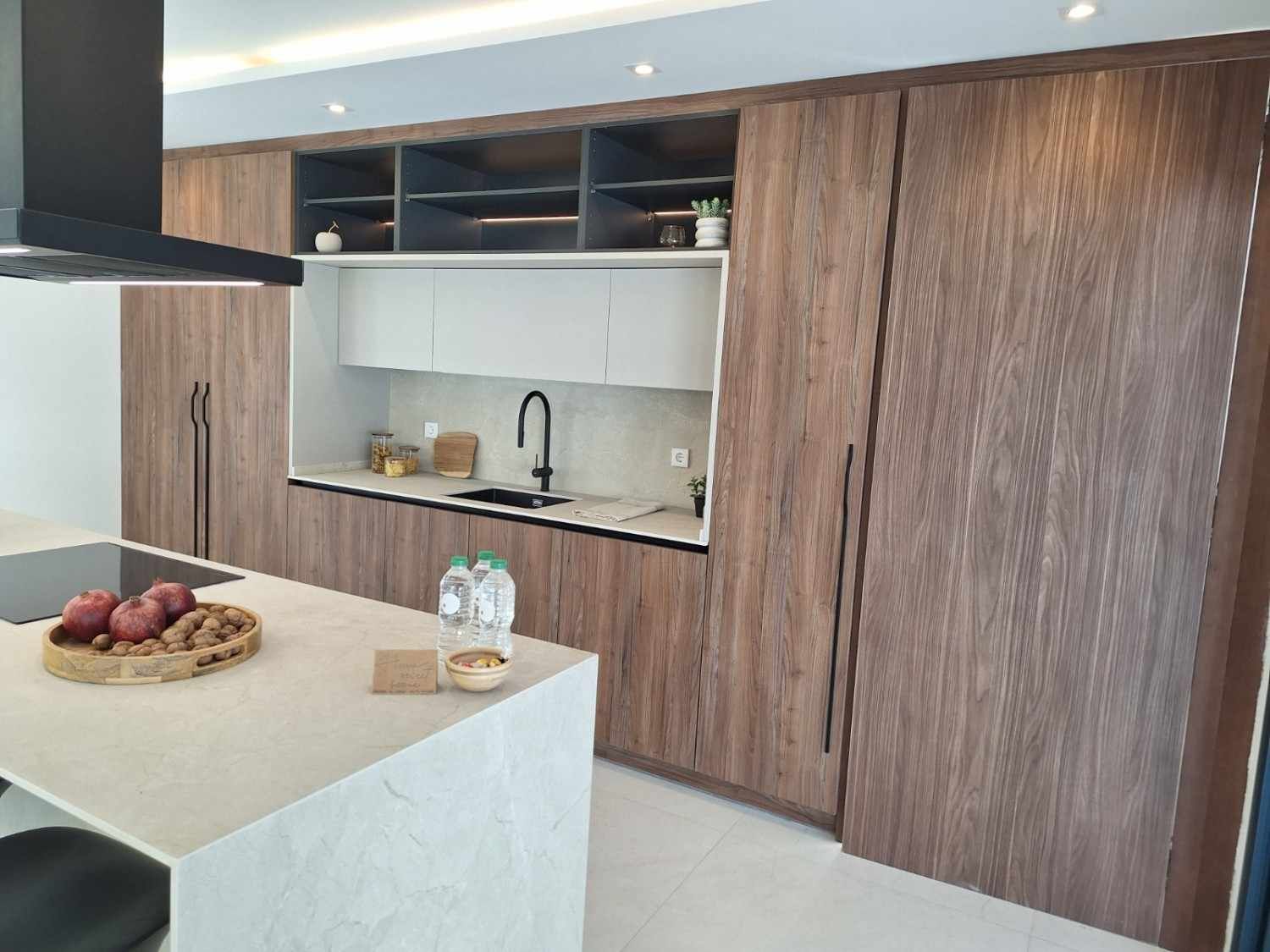 Cocina moderna con armarios de madera, isla grande, fregadero y un frutero sobre la encimera.