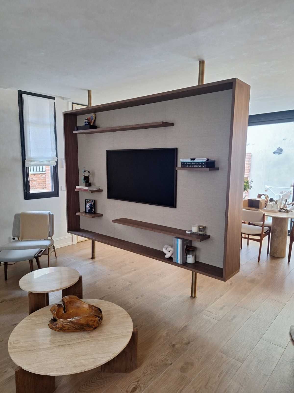 Sala de estar moderna con mampara de TV flotante, mesas de centro y grandes ventanales con vistas a la ciudad.