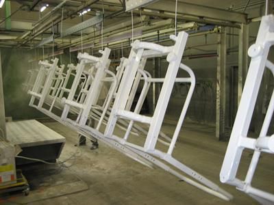 Eine Reihe weißer Stühle hängt von der Decke einer Fabrik.