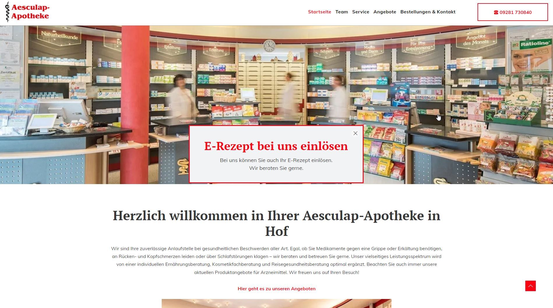 Innenansicht der Aesculap Apotheke in Hof, Deutschland. Regale mit Produkten, Mitarbeiter an der Theke.