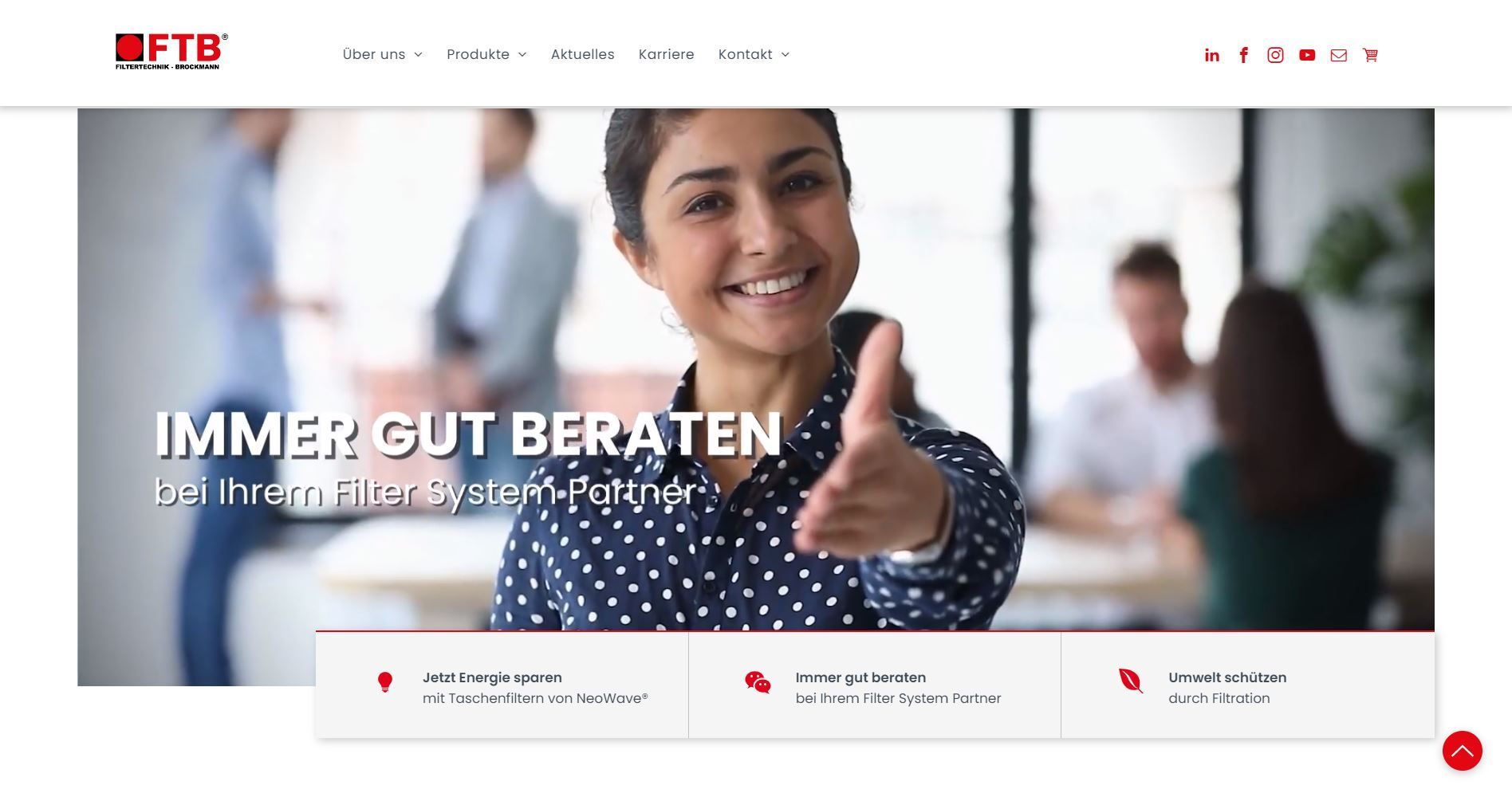 Frau streckt Hand aus und lächelt in die Kamera, im Hintergrund sind Teammitglieder unscharf. Website-Header: FTU.