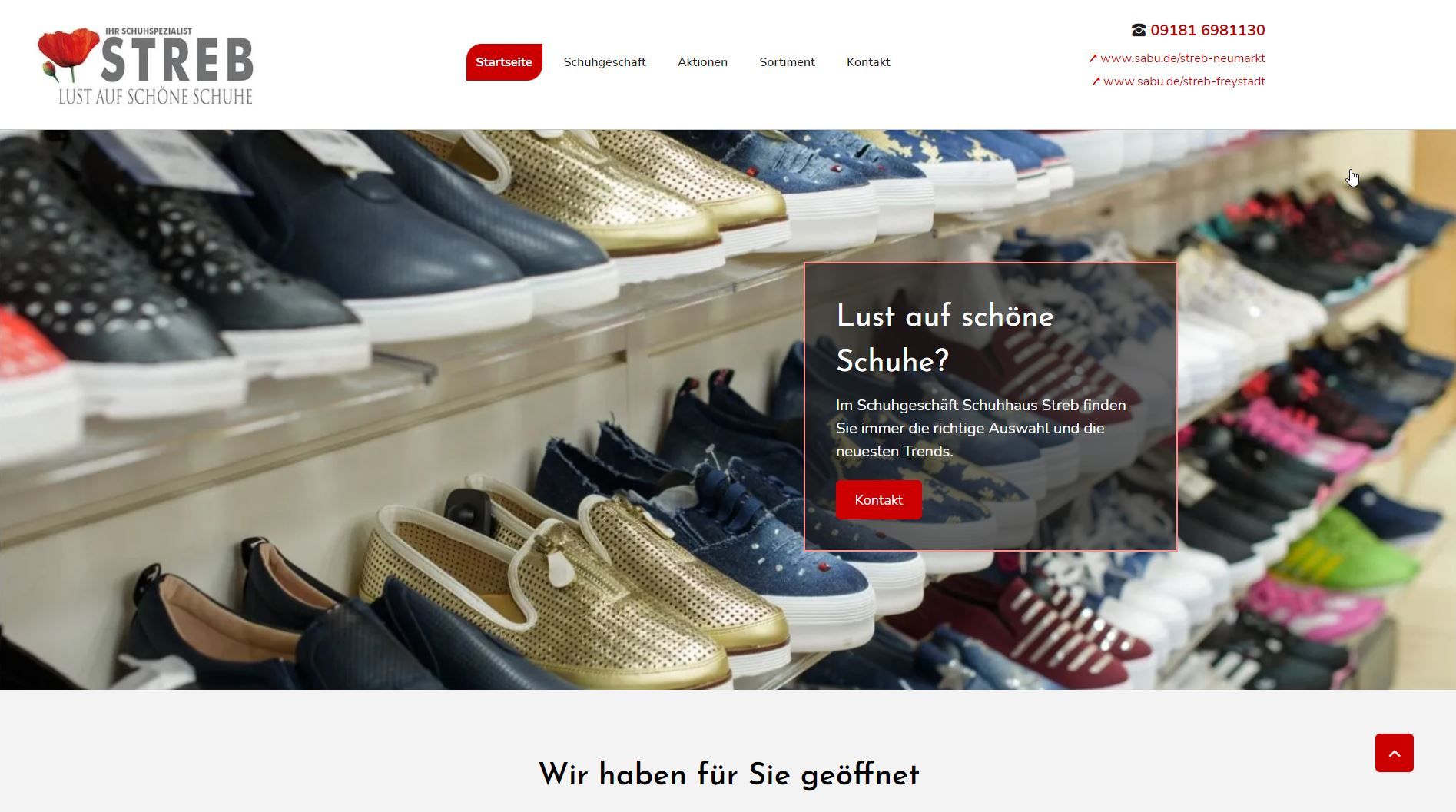 In einem Geschäft werden Schuhe in Regalen mit einem Werbebanner und dem Firmenlogo ausgestellt.