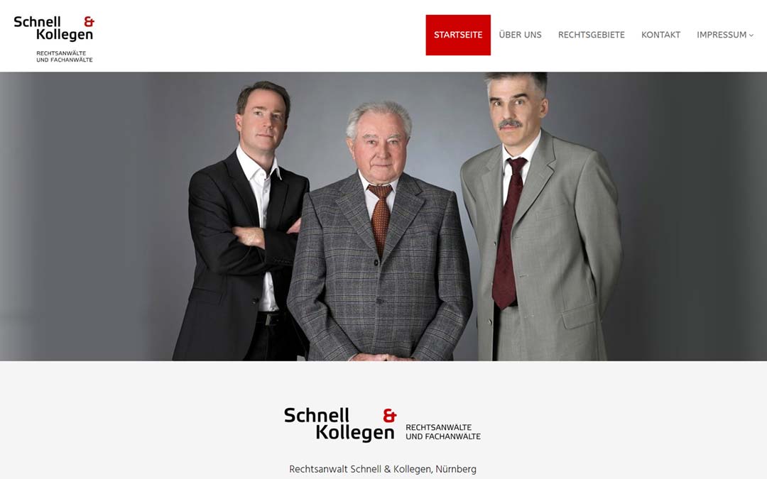 Drei Männer in Anzügen, wahrscheinlich Anwälte, stehen vor einem grauen Hintergrund.