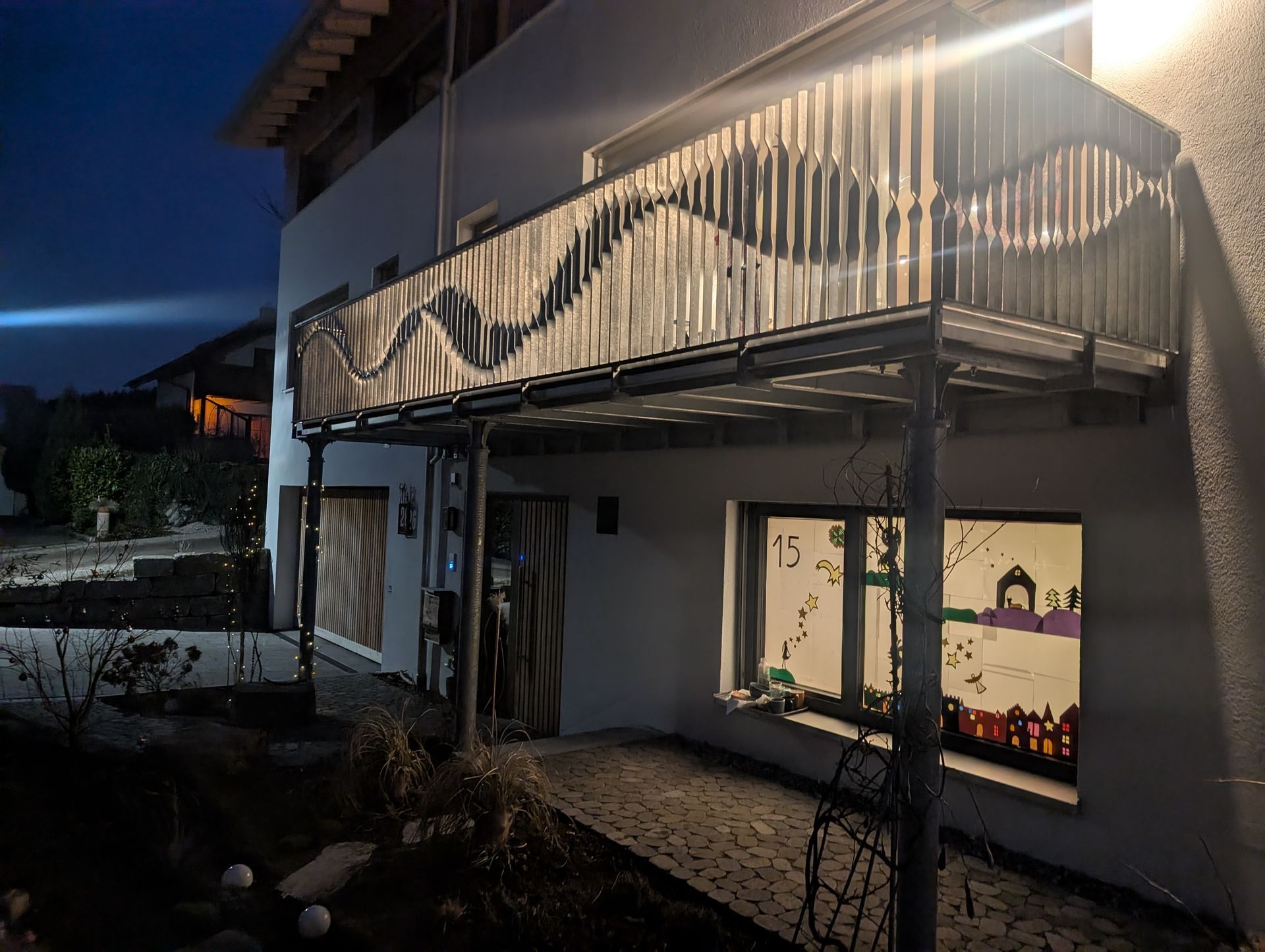 Moderner Balkon mit beleuchtetem Metallgeländer in Wellenform bei Nacht