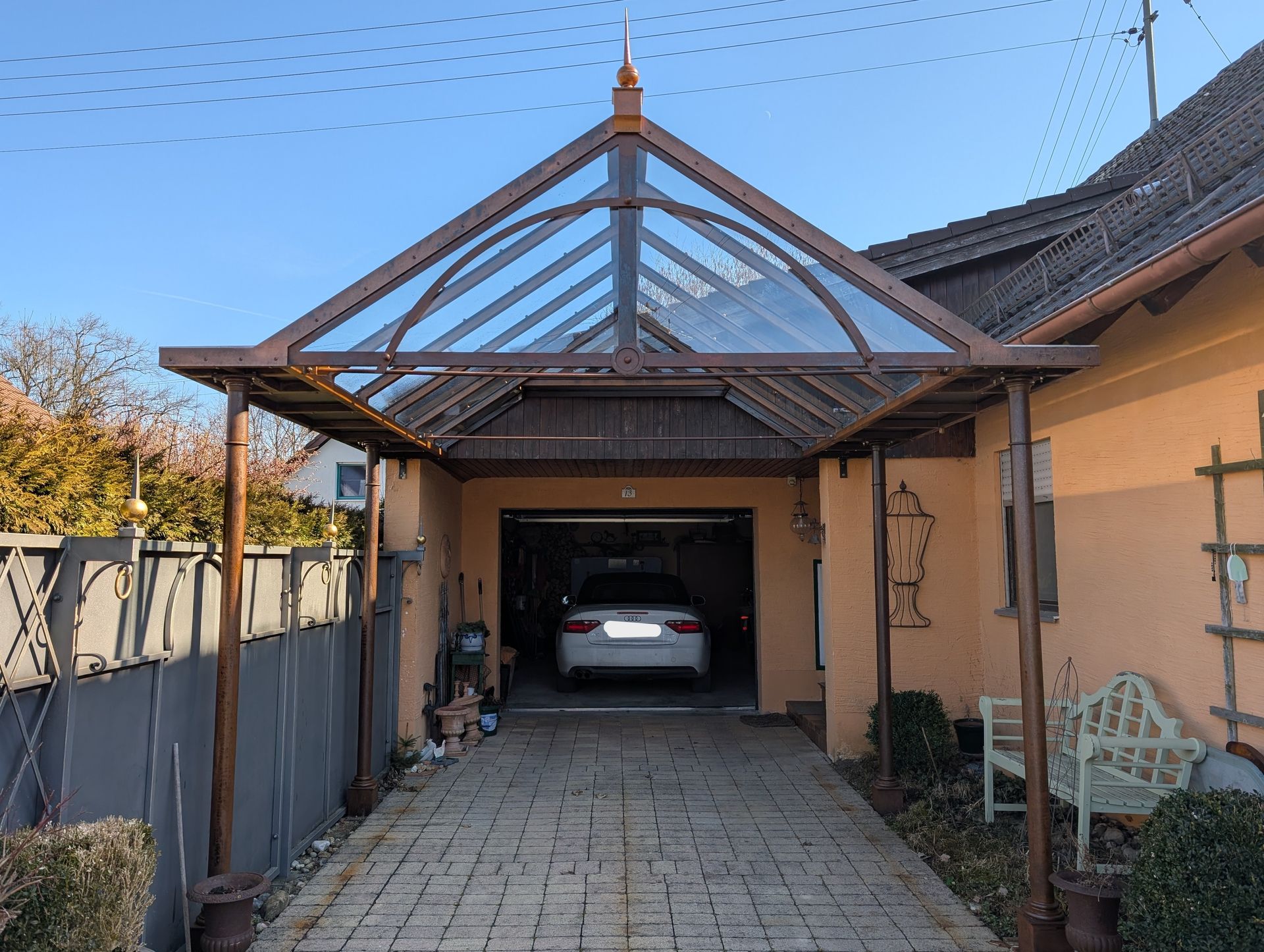 Carport mit Glasdach und Metallrahmen vor Garage