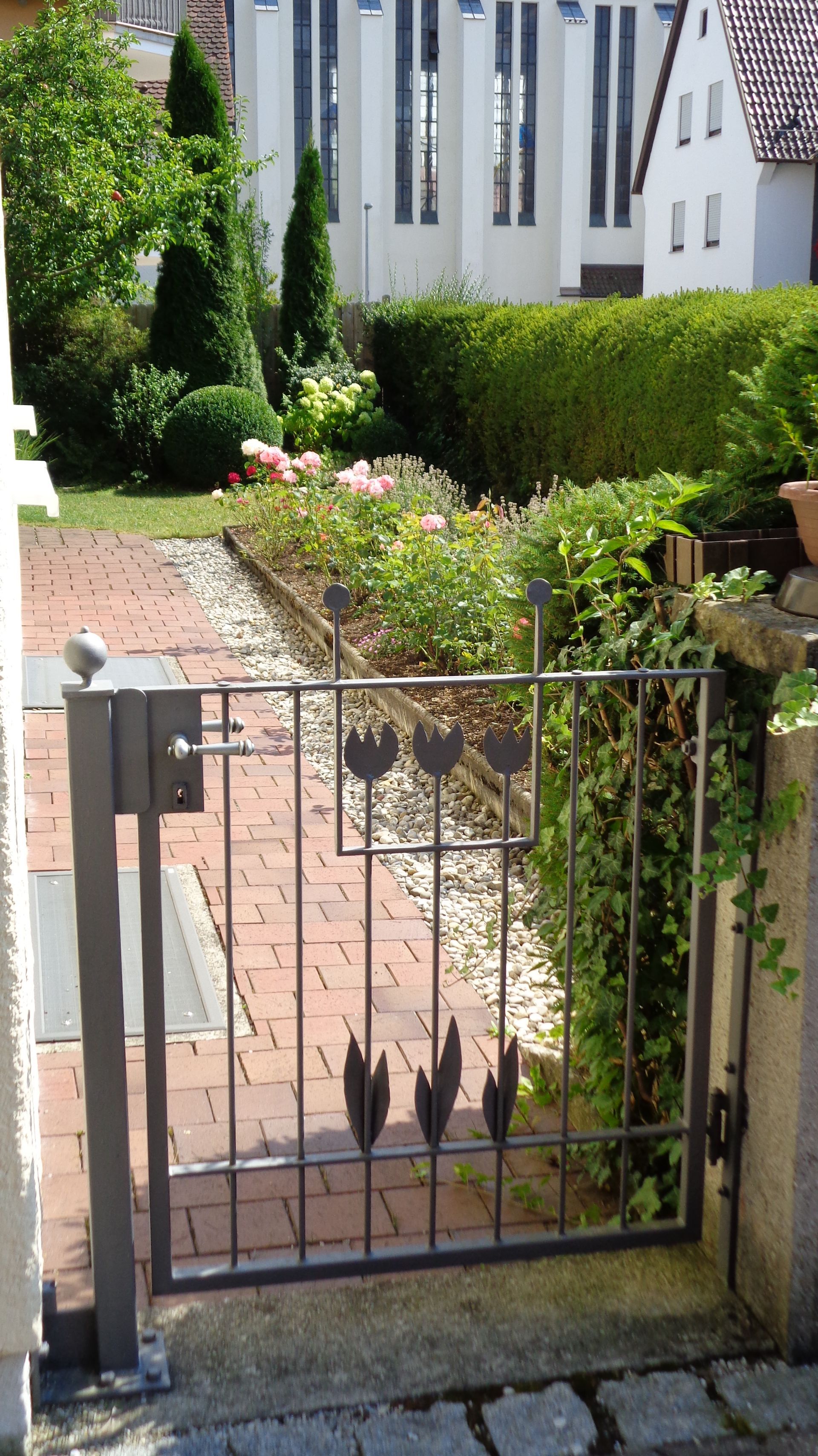 Kleines Gartentor mit Tulpenmotiv entlang Gartenweg