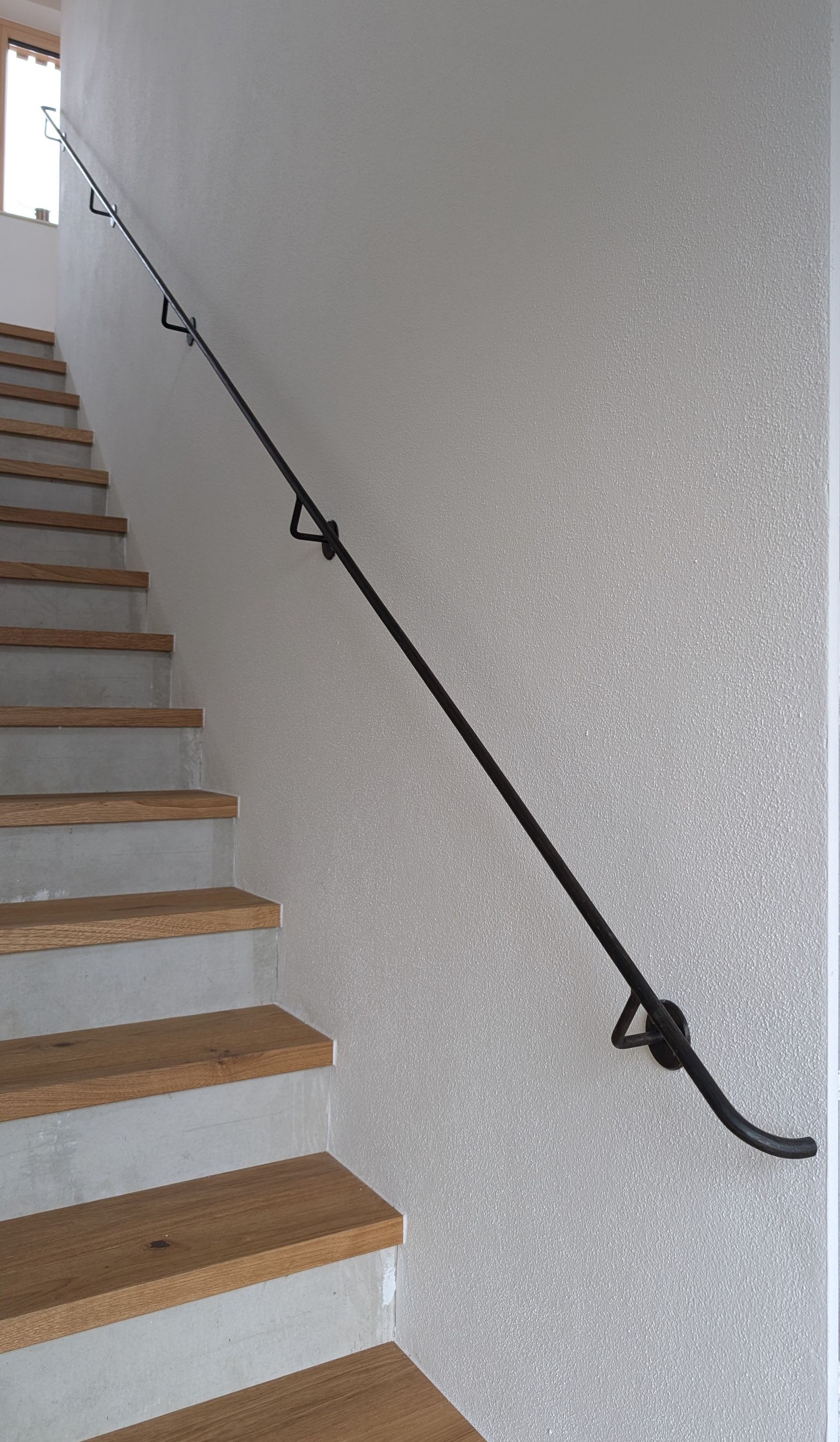 Gerader Metallhandlauf an Holztreppe im Innenraum