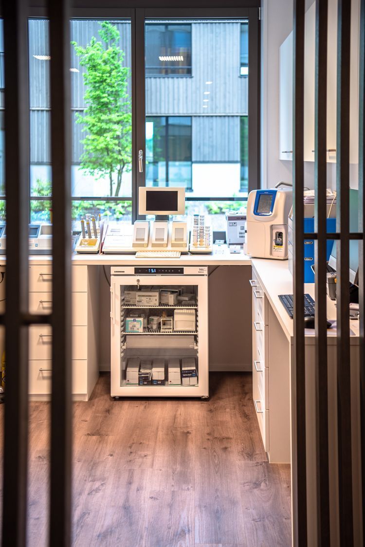 Ein Labor mit einem Kühlschrank und einem Computer auf einem Schreibtisch.