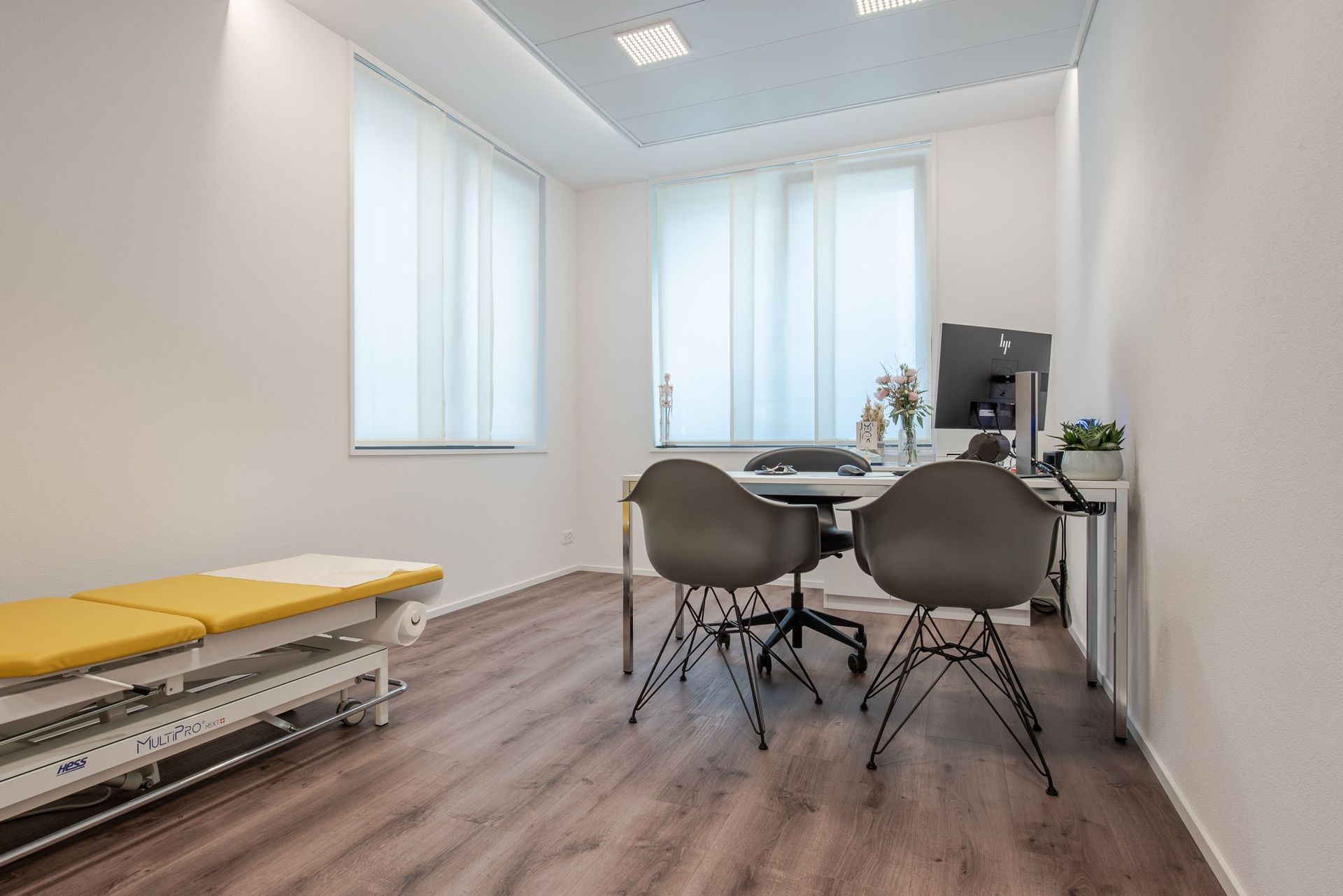 Eine Arztpraxis mit einem Tisch, Stühlen und einem Computer.