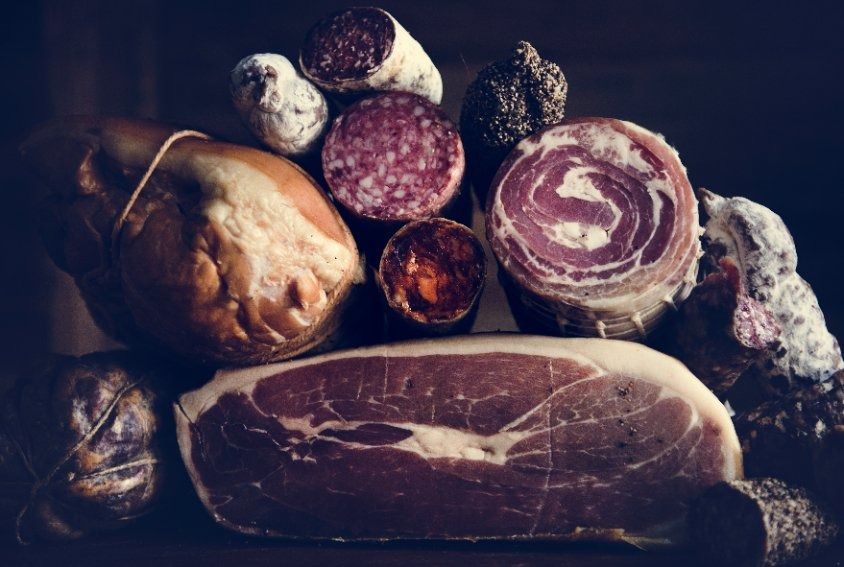 Una variedad de carnes y embutidos están sentados sobre una mesa.