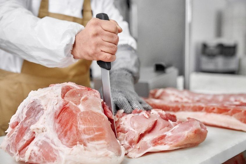 Un carnicero está cortando un trozo de carne en una tabla de cortar.