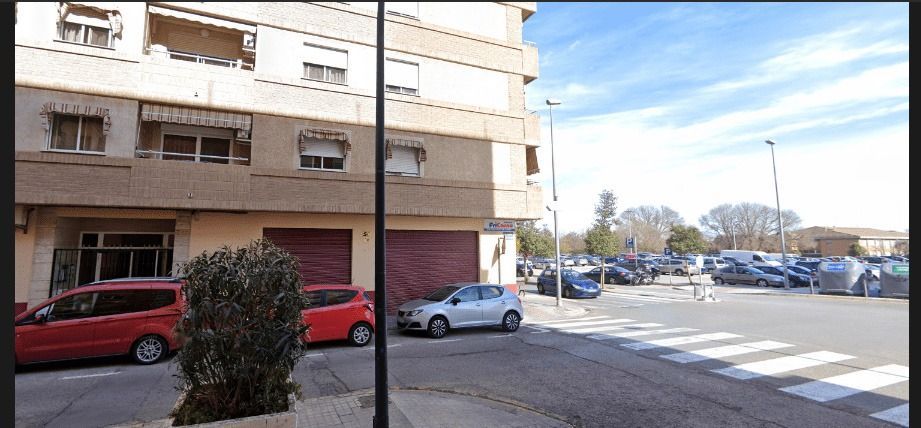 Un edificio con muchos coches aparcados delante.