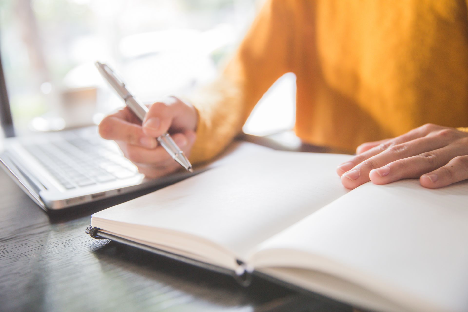 Image d'une femme tenant un stylo devant un cahier
