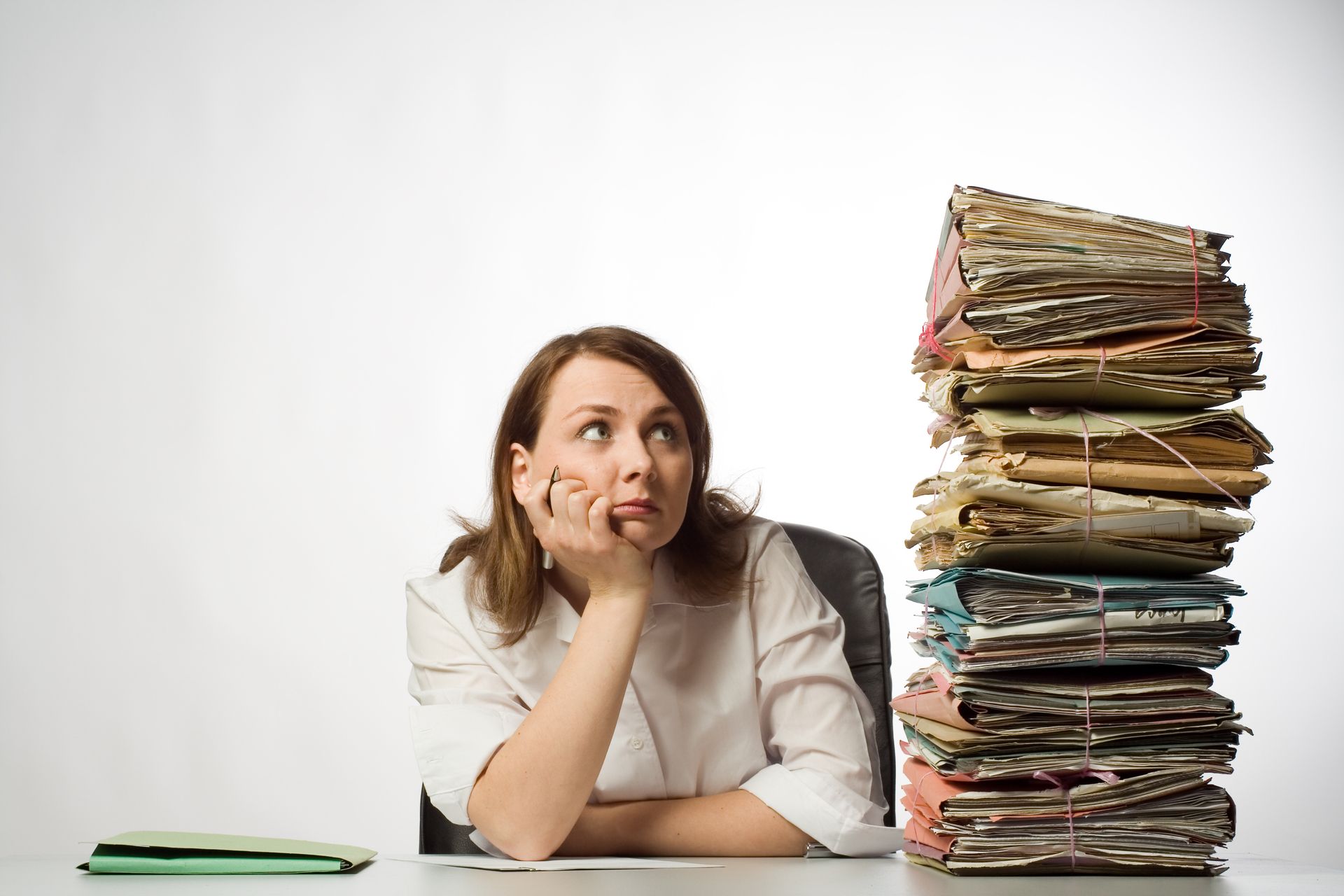 Image d'une femme regardant d'un air abattu une grande pile de dossiers