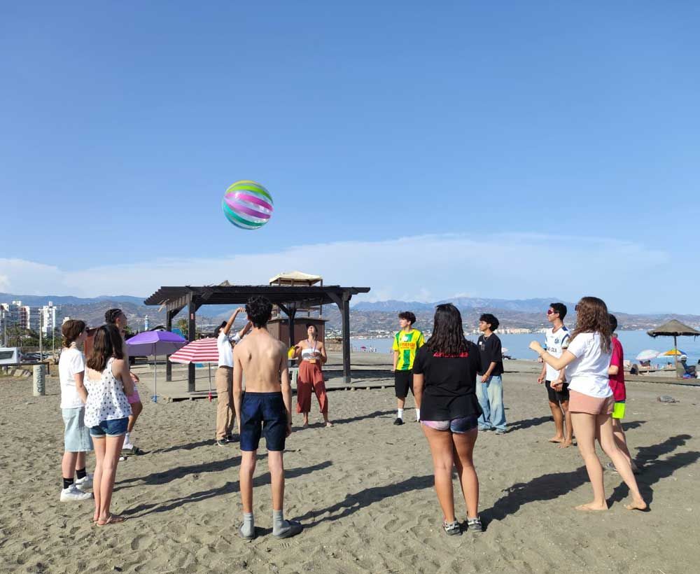 Gente jugando voleibol de playa con una pelota en una playa soleada.