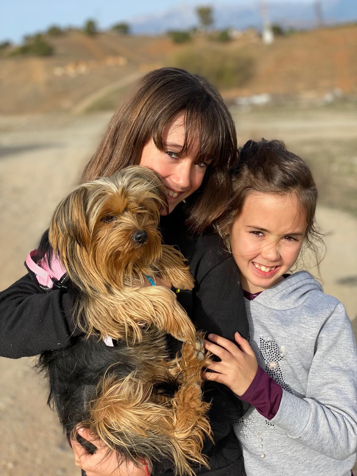 Tres personas están cerca de un árbol frutal. La persona del medio sostiene una fruta. Día nublado.