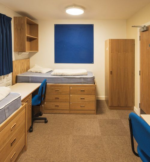 Dormitorio con cama, escritorio, armario y detalles en azul.