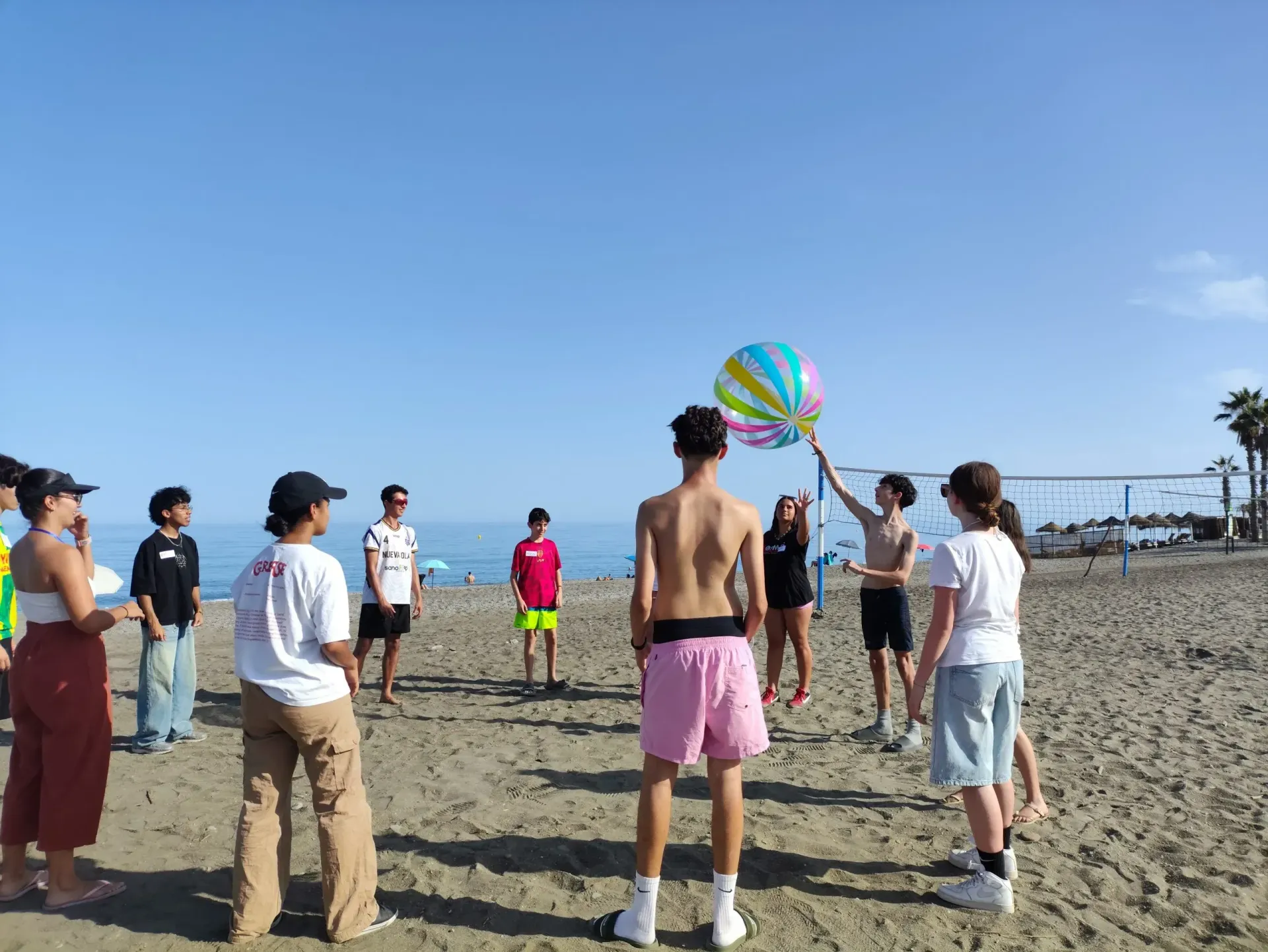 Gente jugando al voleibol con una pelota de playa en una playa soleada.