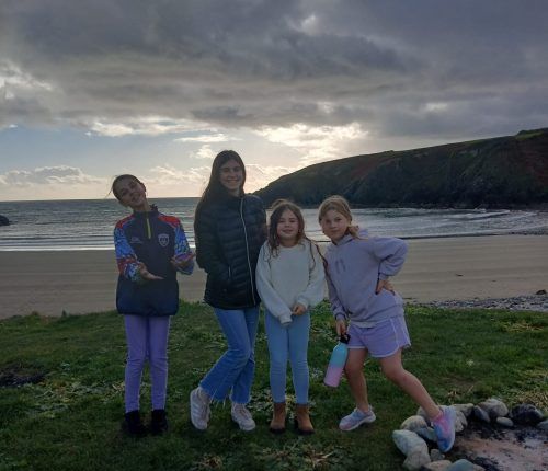 Cuatro personas posan en un césped junto a la playa. Cielo nublado y océano de fondo.
