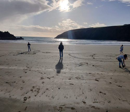 Gente en una playa de arena en un día soleado. Montaña al fondo.