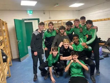 Grupo de futbolistas con uniformes verdes y negros posando en el interior de un vestuario.