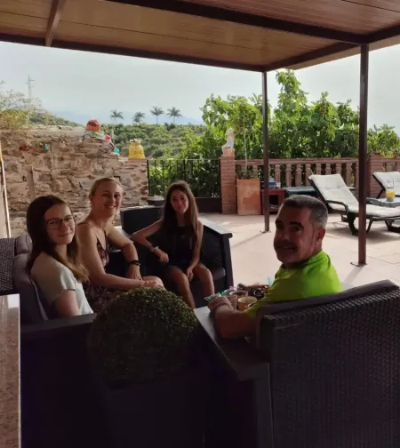 Gente relajándose en un patio sombreado con tumbonas y vegetación tropical al fondo.