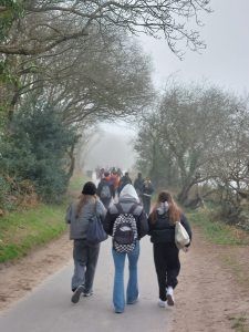Gente caminando por un sendero bordeado de árboles, un día de niebla.