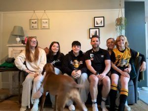 Familia sentada en un sofá con un perro; sala de estar en tonos neutros.