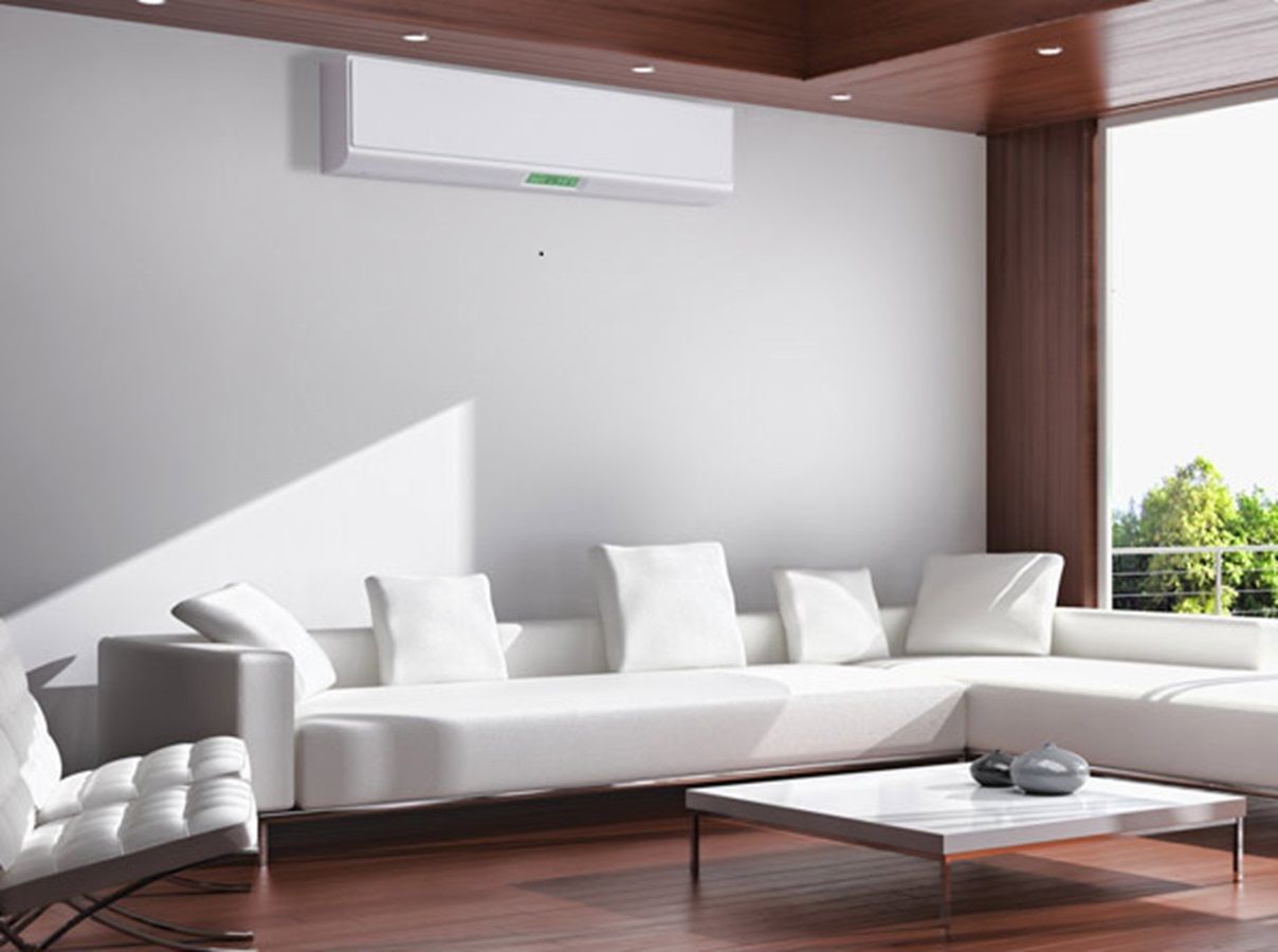 Salon moderne avec canapé d'angle blanc, climatisation et grande fenêtre.