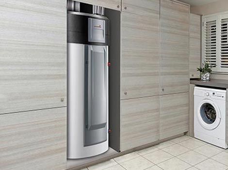 Chauffe-eau installé dans un placard de la buanderie, à côté d'une machine à laver.