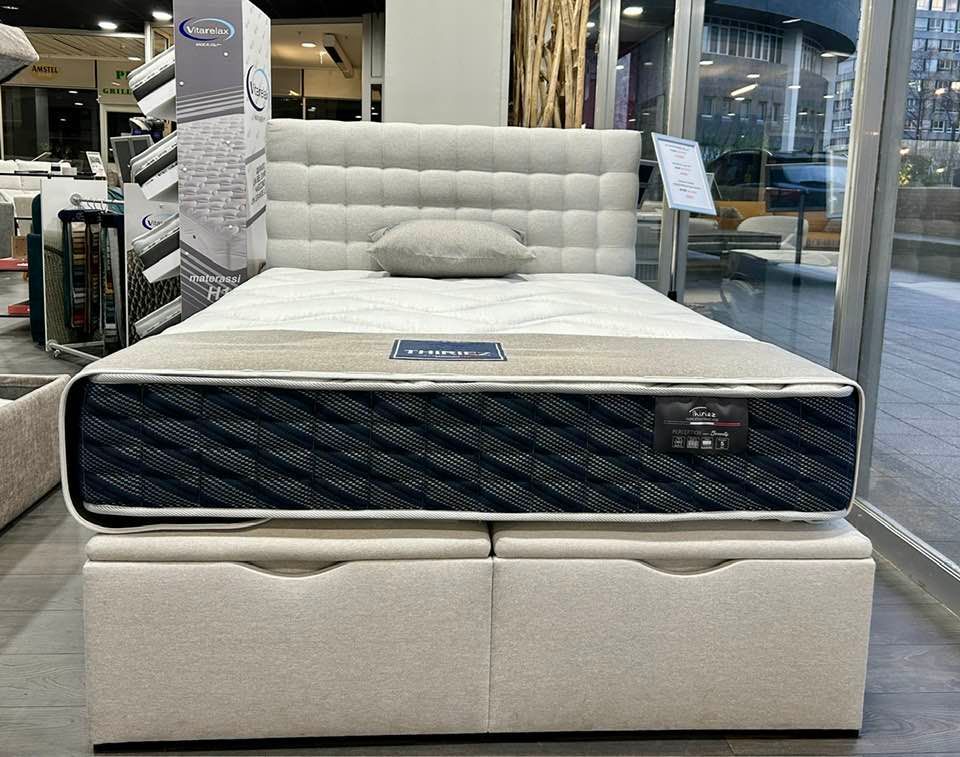 Grand lit beige avec des tiroirs.