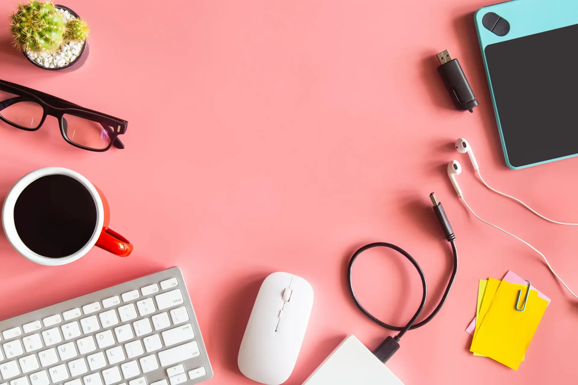 Vista cenital de un espacio de trabajo sobre un fondo rosa con un teclado