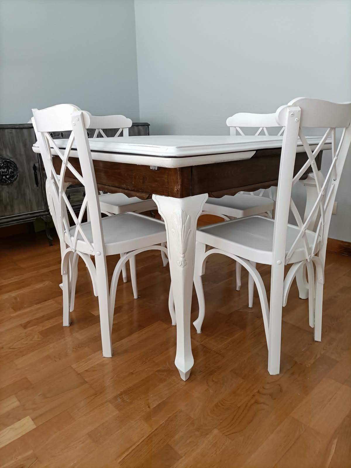 Sillas blancas alrededor de una mesa de comedor de madera en una habitación luminosa con suelo de madera dura