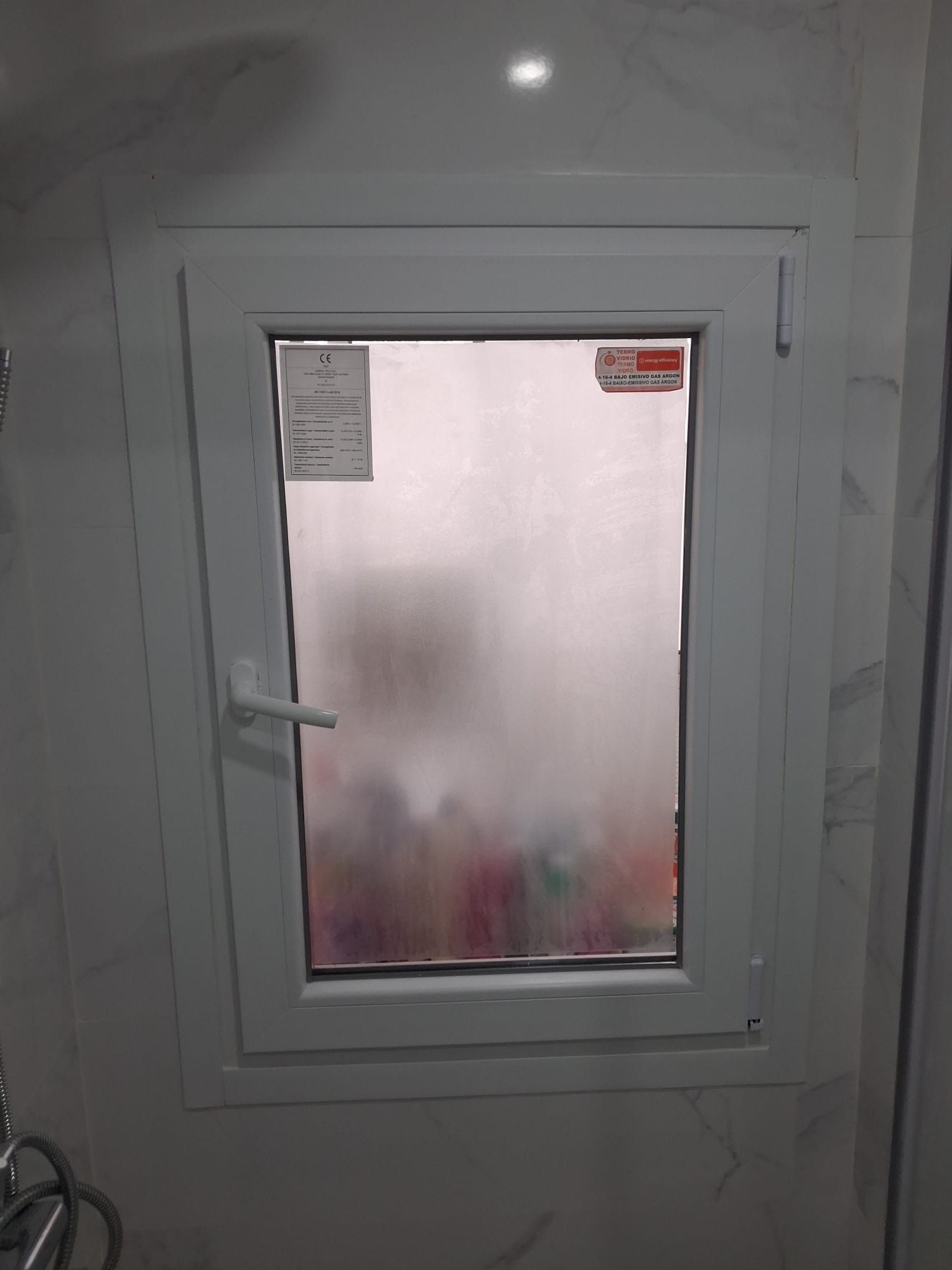 Puerta blanca pequeña con una ventana de vidrio esmerilado en un pasillo interior sencillo.