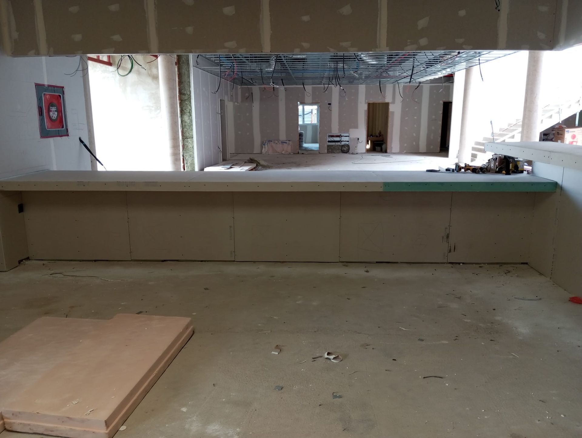 Habitación vacía sin terminar, con una encimera o plataforma elevada, paredes al descubierto y materiales de construcción en el suelo