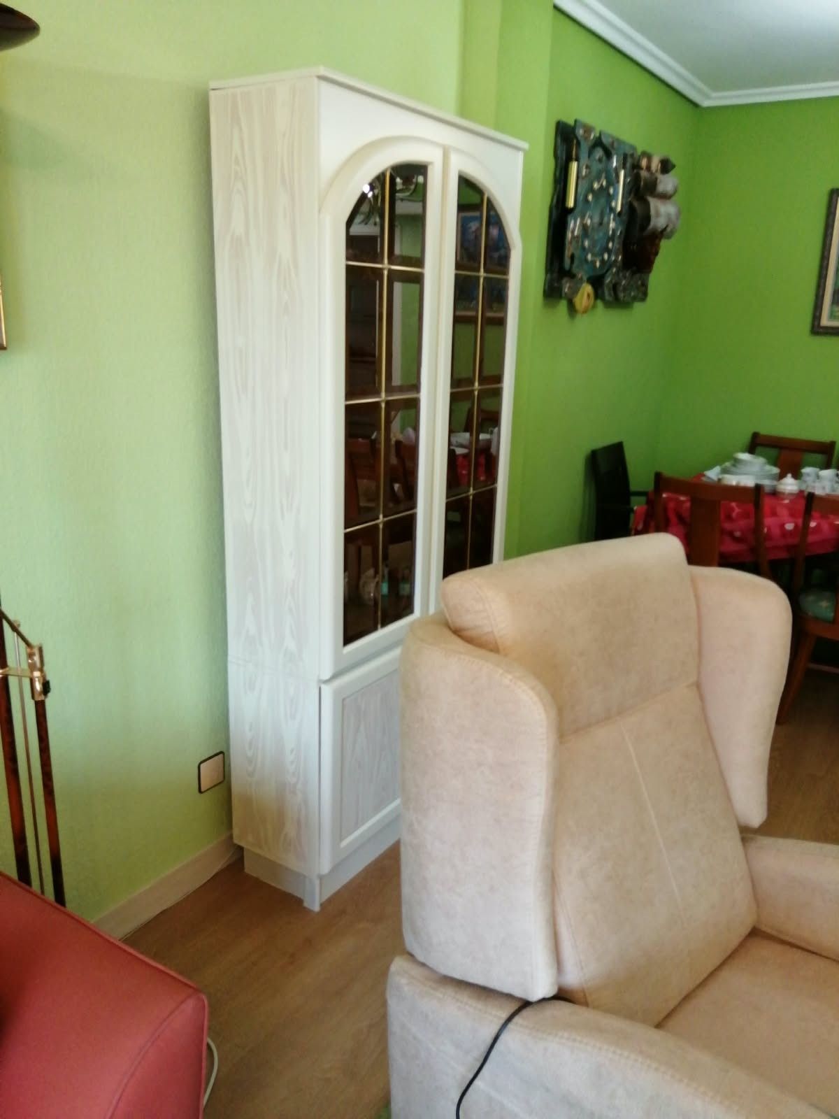 Salón con paredes verdes, un mueble blanco, sillas beige y el borde de un sofá rojo