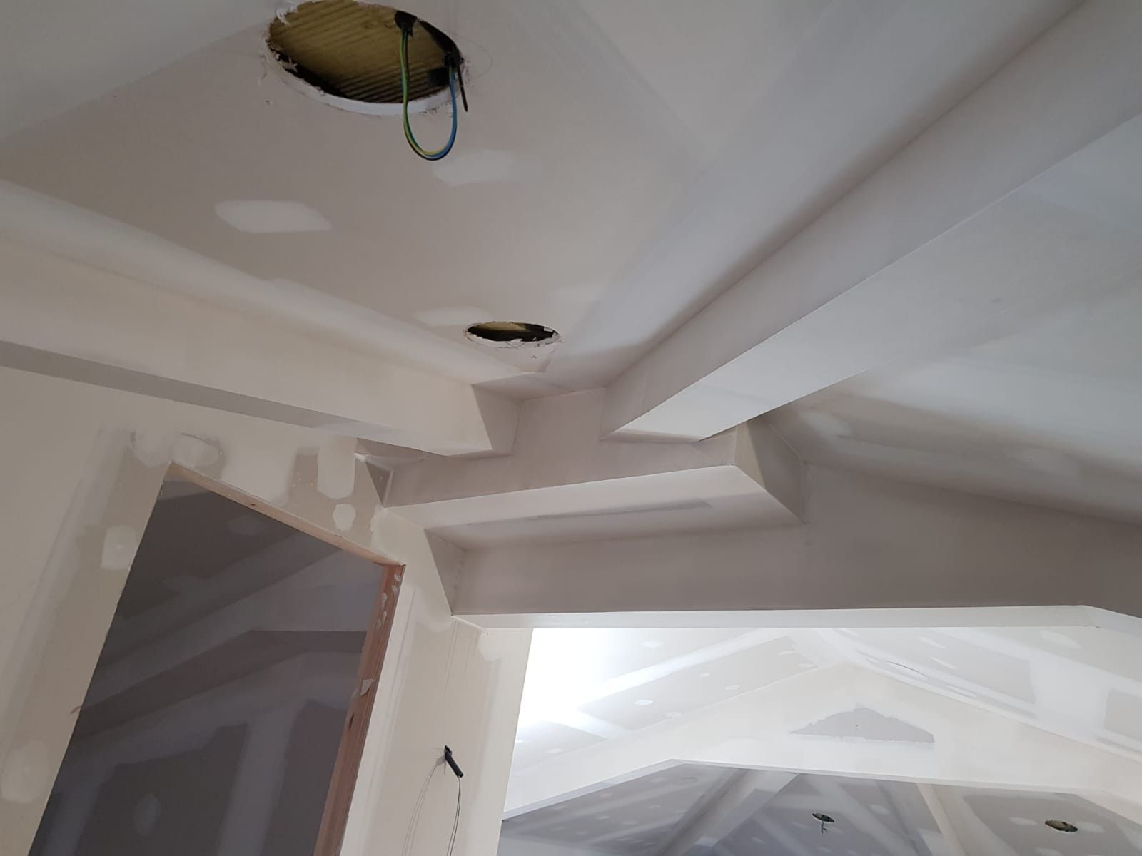 Techo dañado, con agujeros abiertos y cables expuestos en una habitación blanca