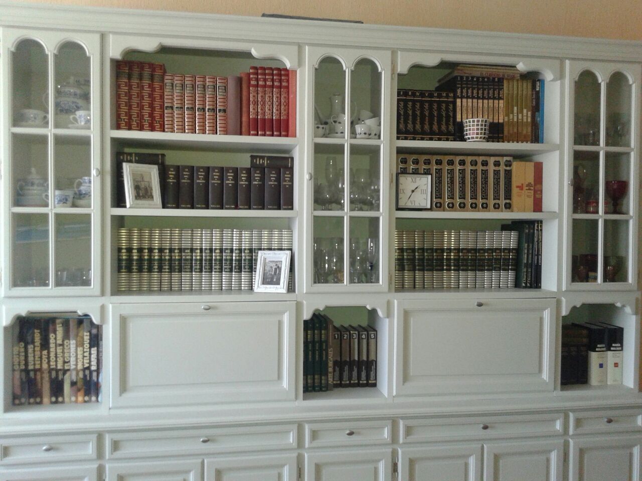Estanterías blancas empotradas llenas de libros y vitrinas en un salón