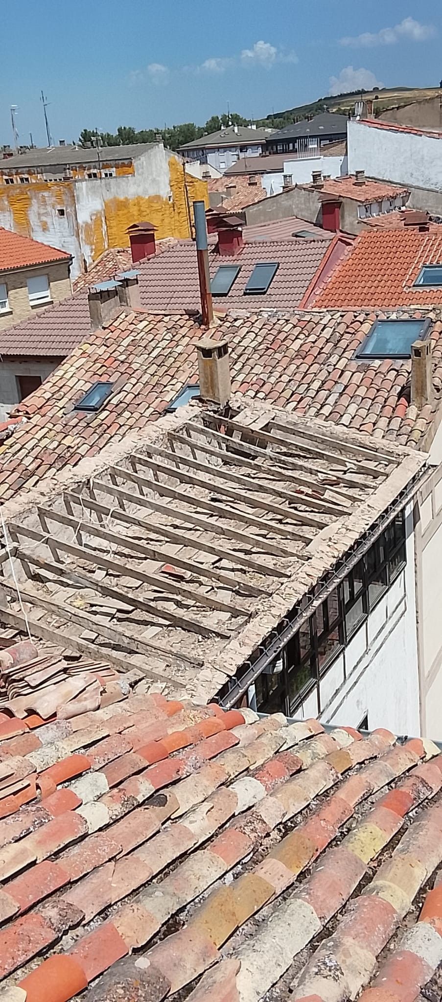 Tejados con tejas rojas desgastadas en un barrio en la ladera bajo un cielo azul