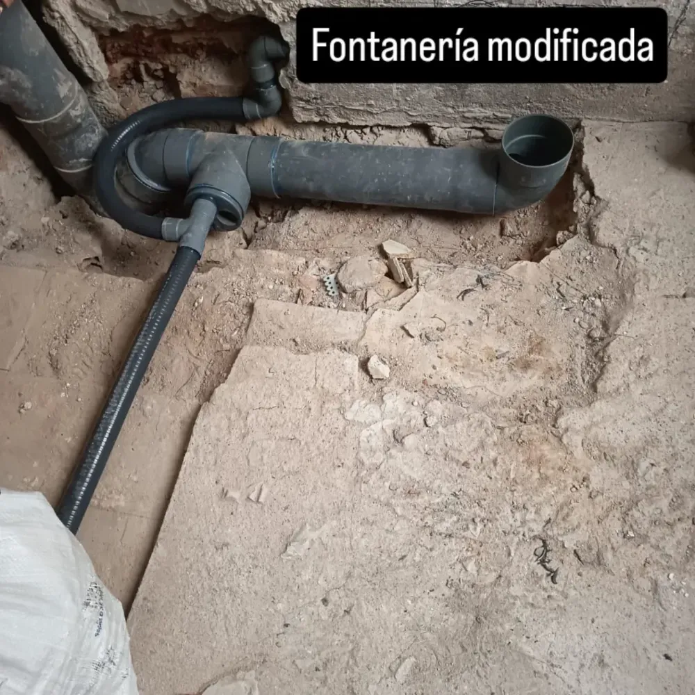 Fontanería modificada: tuberías grises expuestas sobre suelo de cemento en obra.