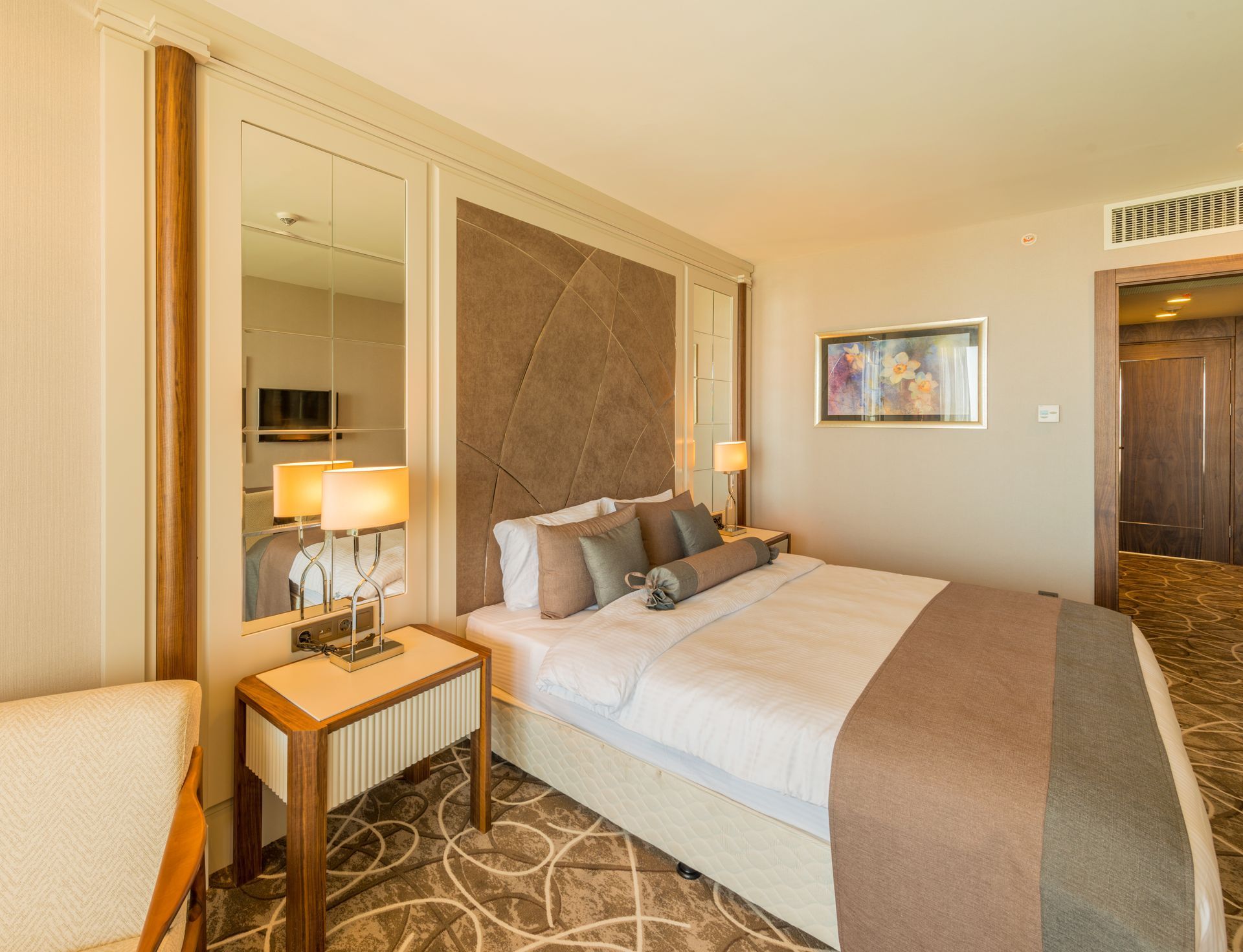 Hotelschlafzimmer mit Bett, Nachttisch, Spiegel und Tür.