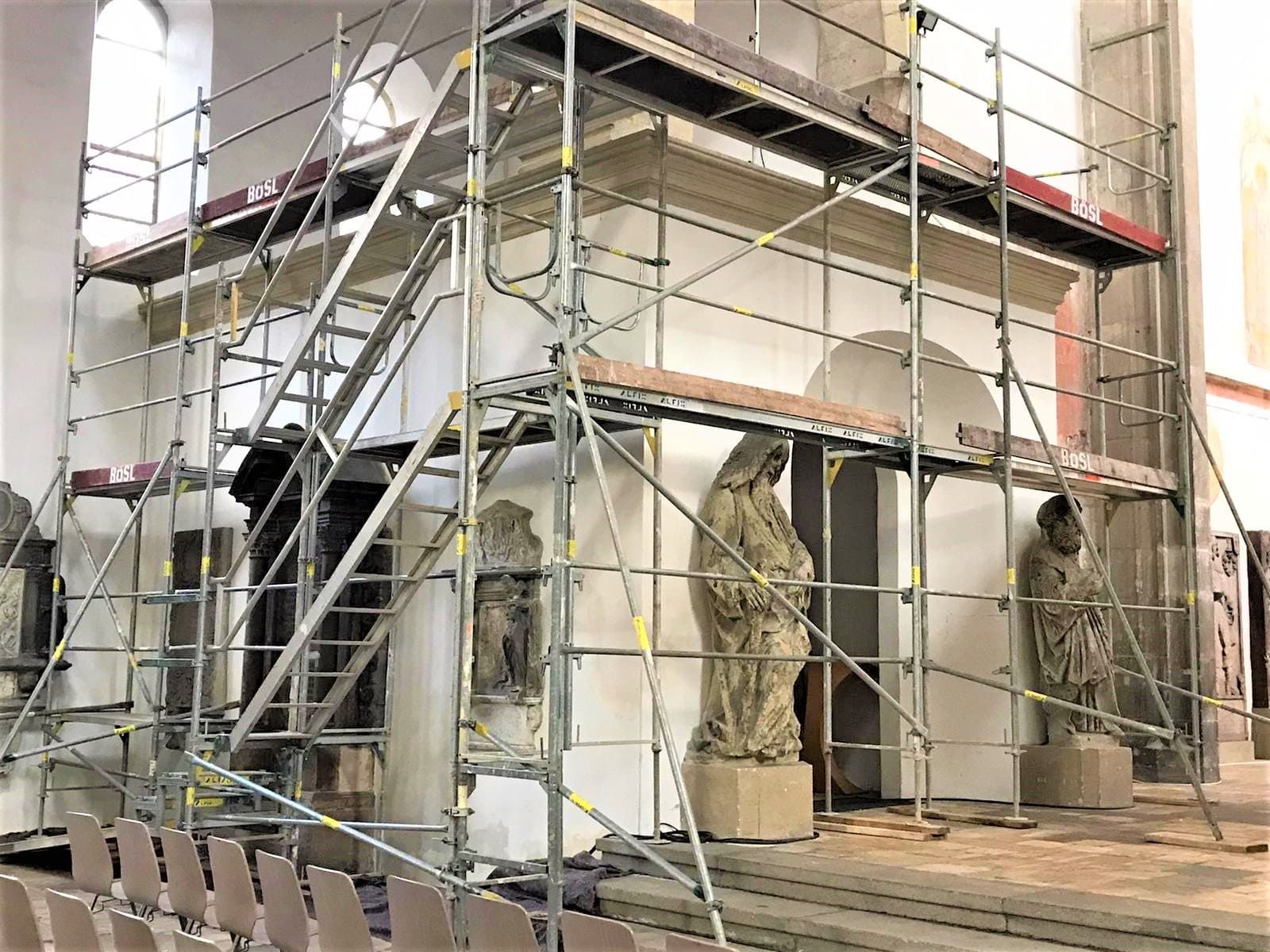 Ein Gerüst umgibt eine Kapelle mit Statuen, die im Inneren eines Gebäudes repariert werden.