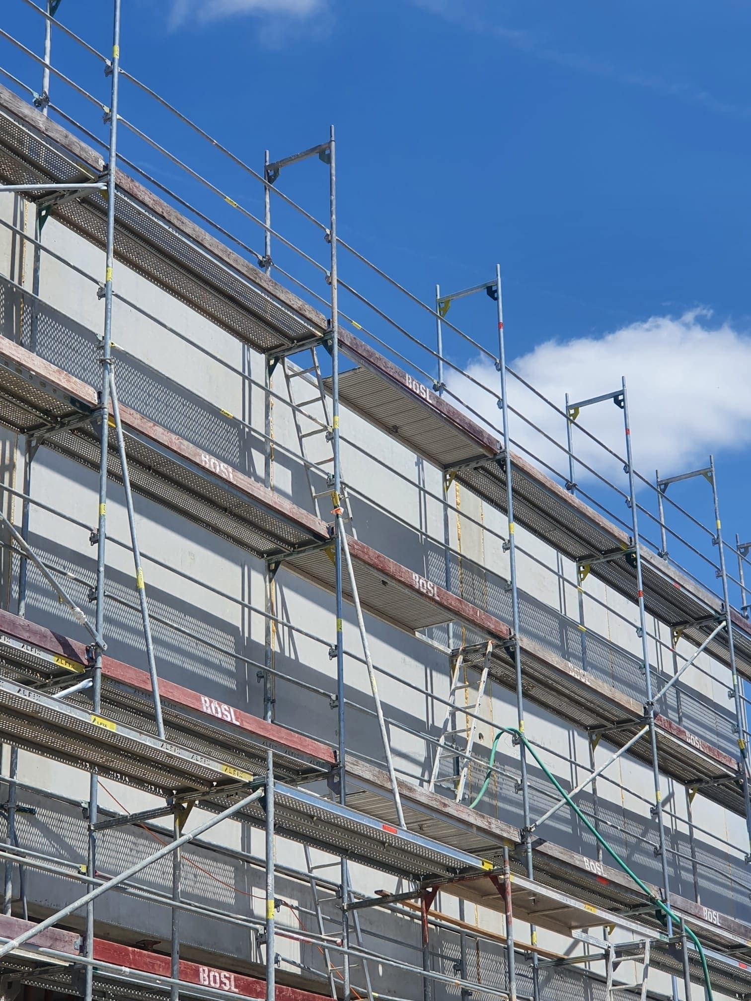 Gerüst an der Seite eines Gebäudes vor blauem Himmel mit einigen Wolken.