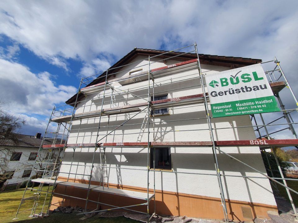 Haus mit Gerüst beim Streichen, mit Schild „BÜSL Gerüstbau“.