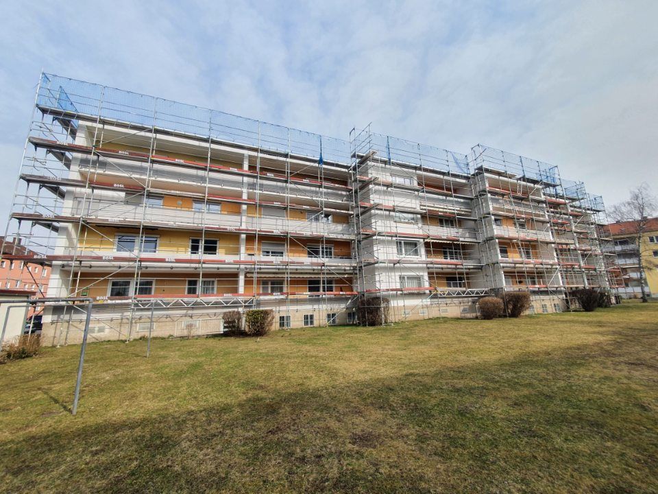 Gebäude im Umbau mit Gerüst, blaue Sicherheitsnetze.