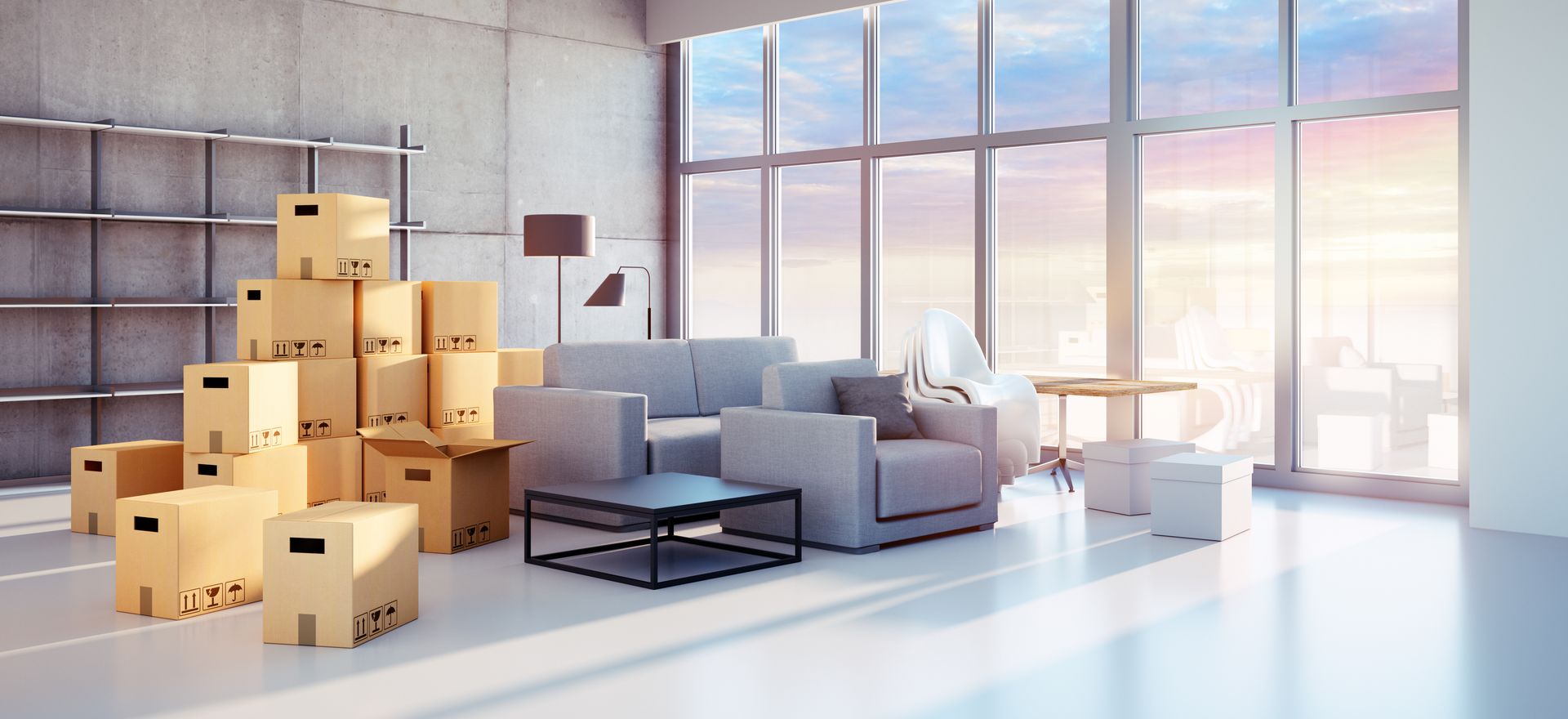 In einem modernen, sonnigen Loft mit großen Fenstern und Blick auf die Stadt sind neben einem Sofa gestapelte Kisten.